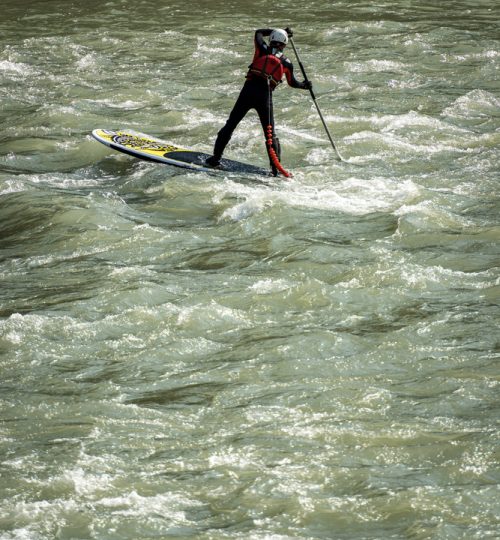 VERONA, ITALY - SEPT 19, 2020: a man on his Stand up Paddleboarding (SUP), paddles in the rapids of the Adige river in Verona downtown. Veneto, Italy, Europe